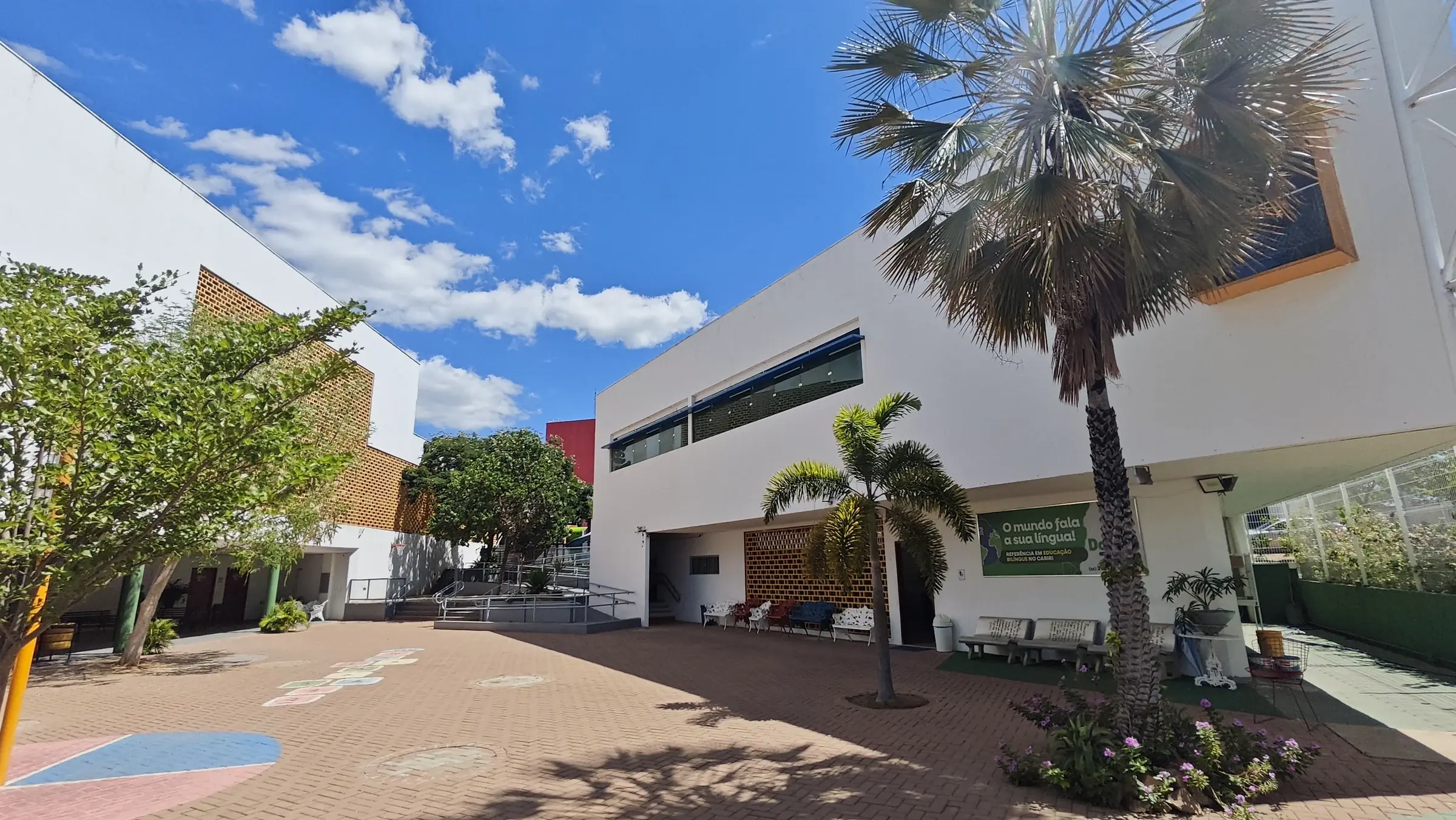 Pátio interno do Colégio Domum, com palmeiras, cobogós e os prédios da escola